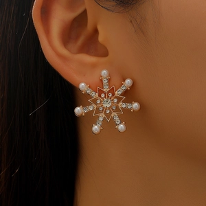 Close-up of a gold snowflake earring with pearls and rhinestones on a female model