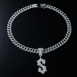 Close-up of iced-out silver Cuban chain with sparkling dollar sign pendant on black surface
