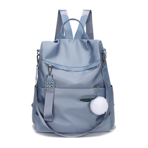 Light blue nylon backpack with rivet details and white pompom charm on white background