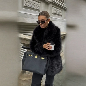 Femme élégante en manteau de fourrure noire et sac à main en cuir en ville