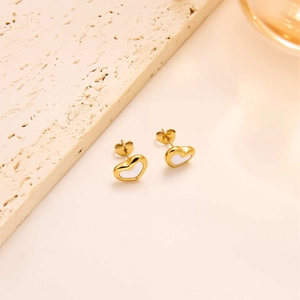 Detailed view of heart-shaped gold stud earrings featuring white mother of pearl inlay
