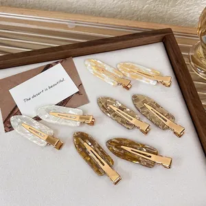 8-piece set of colorful acetate hair clips with marble texture on a wooden tray