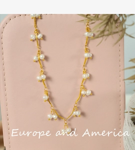 Detail of freshwater pearl necklace with golden wavy links on a pink leather background