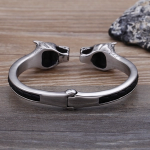 Detailed close-up of double wolf head stainless steel bracelet with black weave pattern