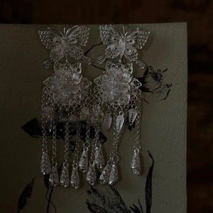 Close-up of hollow butterfly and flower tassel earrings with intricate silver metal ethnic details