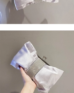 Detail einer silbernen Satin-Abendtasche mit Schleife und Strass-Verzierung