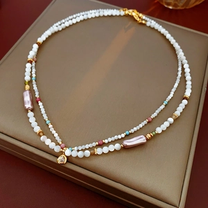 Close-up of double layer pearl necklace with colorful beads and gold diamond pendant