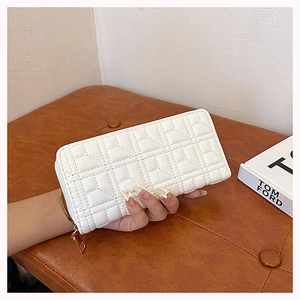 Detailed view of white quilted long wallet with Y-pattern and golden zipper closure