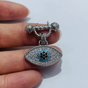 Makro-Detail des silbernen Evil Eye-Anhängers mit weißen und blauen Schmucksteinen