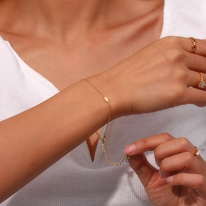 Close-up of 18K gold plated stainless steel thin bracelet with oval charm on wrist