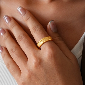 Close-up of 24k gold plated wave ring with frosted texture on woman's finger