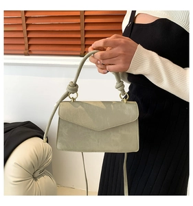Vue détaillée du sac en daim avec poignée nouée et anneaux métalliques dorés élégants
