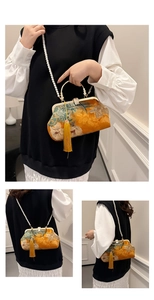 Detail of embroidered floral shell bag with pearl chain strap and silk tassel accent
