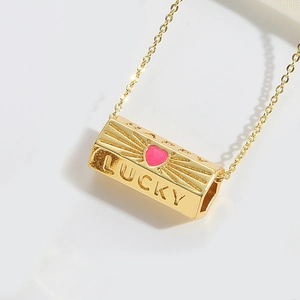Detailed close-up of a gold Lucky pendant with a pink heart and zircon inlay