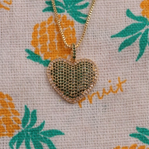 Golden heart necklace featuring green and clear zircon crystals on pineapple fabric