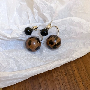 Detail shot of leopard print ball earrings with resin spheres and silver needle pins