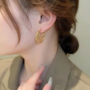 Polished gold hollow C-shaped earrings with iconic letter logo on female model