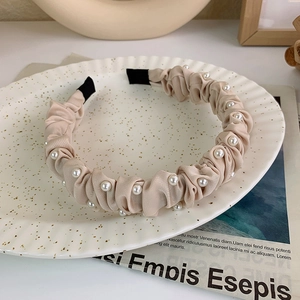 Cerchietto in tessuto increspato champagne con perle bianche su piatto di ceramica