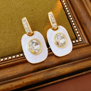 Gros plan de boucles d'oreilles vintage en or avec diamant ovale sur émail blanc et velours