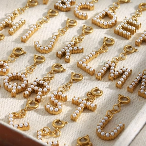 Macro view of gold plated A-Z letter charms with pearls and spring clasps for DIY jewelry