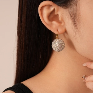 Gros plan de boucles d'oreilles boules en cristal champagne portées par un mannequin