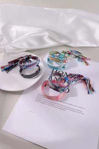 Artistic close-up of five handmade colorful bohemian braided friendship bracelets with tassels