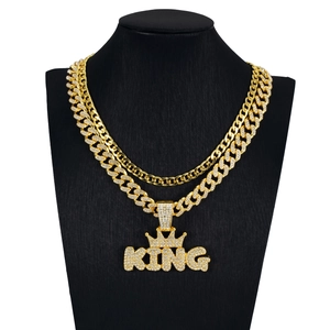 Nahaufnahme der goldenen Cuban-Kette mit vereistem KING-Kronenanhänger auf schwarzem Modell