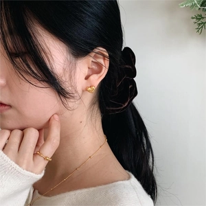 Lifestyle shot of model wearing 925 silver heart bow earrings and beaded ring in gold