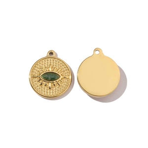 Detail of golden circular pendants featuring green oval gemstone and textured eye design
