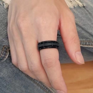 Macro detail of men's black titanium steel ring featuring matte tiered grooves on finger