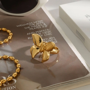 Luxurious gold butterfly stainless steel ring styled on a magazine with bracelets