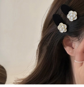 Detail view of pearl camellia hair clips on model's side hair for elegant styling