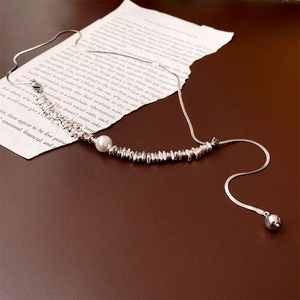 Baroque pearl fringe necklace with silver chain on textured leather and vintage paper background