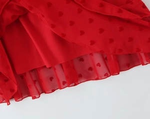 Détail de l'ourlet en maille rouge avec imprimé cœur et bord ondulé d'une robe