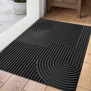 Black geometric textured entryway doormat on wooden floor in home setting