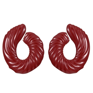 Macro detail of dark red spiral earrings with wavy texture and glossy glazed finish