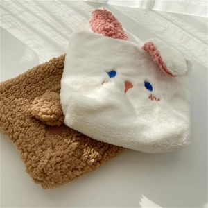Detail of plush rabbit-shaped pouch and brown shearling bag with soft embroidery