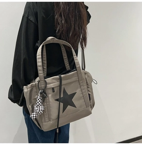 Detail of taupe canvas tote with star pattern and black-and-white checkered charm