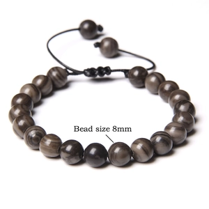 Detail view of 8mm natural tiger eye stone beads on a black braided cord bracelet