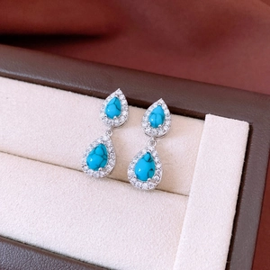 Macro shot of vintage silver-tone teardrop earrings with turquoise stones and zircons