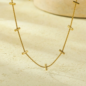 Collana minimalista in acciaio inossidabile dorato con piccoli grani cilindrici in metallo