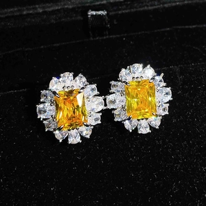 Close-up of yellow rectangular gemstone studs with marquise-cut accents on black velvet