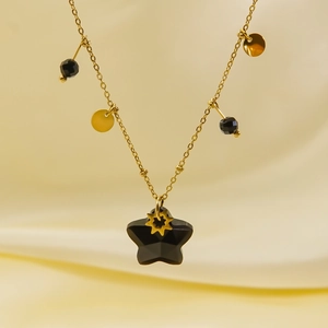 Close-up of pentagram stone pendant with gold sun charm on beaded stainless necklace