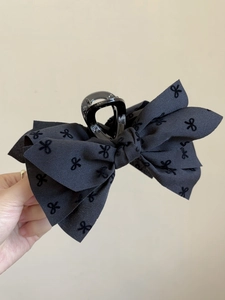 Dettaglio della pinza per capelli in tessuto nero con eleganti motivi a fiocco