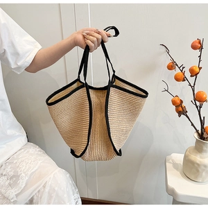 Detail of hand-woven straw tote with black contrast trim and comfortable dual handles