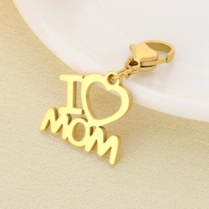 Detailed view of a gold heart-shaped I LOVE MOM pendant with a lobster clasp on fabric