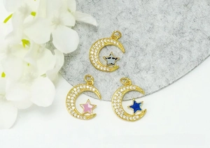Macro detail of three 18K gold-plated star and moon pendants with micro-pave cubic zirconia
