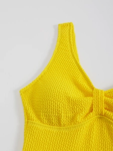Détail du tissu froncé jaune et des coutures sur un maillot de bain une pièce