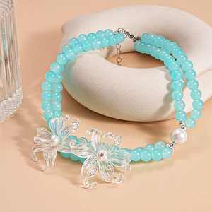 Close-up of double-layer beaded necklace featuring iridescent flower and faux pearls