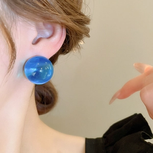 Gros plan détaillé d'une boucle d'oreille sphère en résine bleue avec texture marbrée